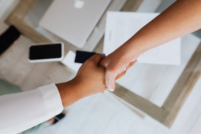 two people shaking hands over documents